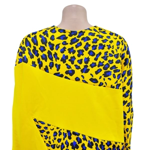 Detail view of bold yellow leopard print top featuring diagonal back splicing design