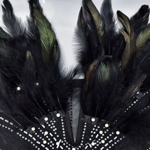Close-up of black mesh dress detailing with rhinestones, pearls and natural feathers