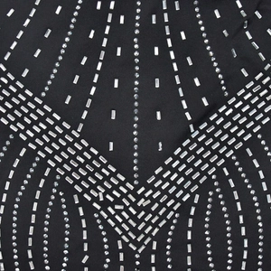 Detail eines schwarzen Netzkleides mit aufwendigen Strasssteinen und funkelnden Kristallen