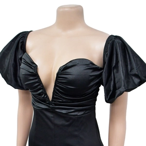 Detail of black mini dress featuring a deep V-neckline and dramatic puff sleeves