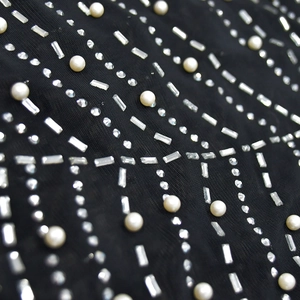 Close-up of black mesh fabric with intricate silver sequins and white pearls decoration