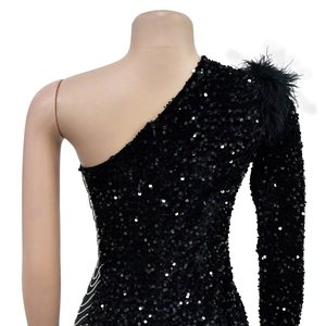 Detail of black sequined dress featuring feather shoulder accents and side chain trim