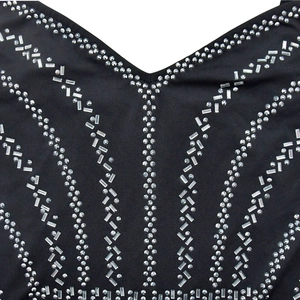 Macro detail of rhinestone patterns and silver sequins on the black bodice fabric