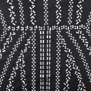 Detailed macro view of silver rhinestones and geometric studs on black knit dress fabric