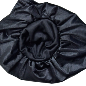 Detail shot of black satin hair bonnet showing pleated elastic edge and silky texture