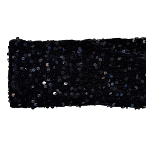 Detailed close-up of shiny black sequins on the fabric of a sexy one-shoulder dress