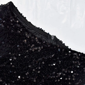 Detail of black sequins fabric featuring ykk zipper and delicate feather trim finish