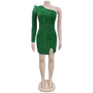 Detailed close-up of emerald green sequin dress with feather shoulder and chain side slit