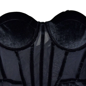Dettaglio ravvicinato di un corsetto in velluto nero con inserti in mesh trasparente