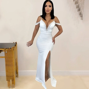 Détail d'une robe blanche avec décolleté en V profond, glands en strass et fente latérale