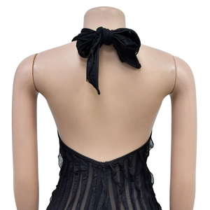 Detail of black backless halter jumpsuit with mesh ruffles and large bow tie closure