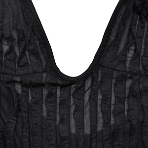 Detailed macro view of the deep V-neckline and pleated sheer fabric texture on a black romper
