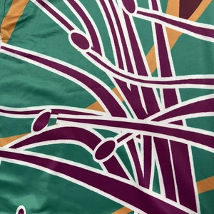 Detailed close-up of abstract geometric print on breathable green mesh polyester fabric