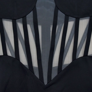 Detailed close-up of the black corset mesh panels and geometric tape stitching