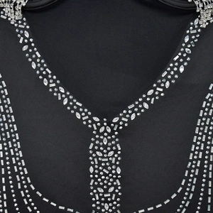 Dettaglio dello scollo a V in tessuto a rete con strass geometrici su un abito nero