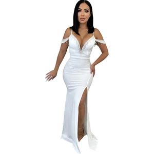 Détails de franges argentées avec strass et perles sur une robe blanche à décolleté plongeant
