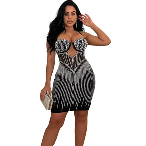 Détails de la robe moulante en mesh noir avec franges de cristal et décolleté en cœur