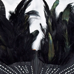 Detail von schwarzen Federn und silbernen Strasssteinen auf einem Gothic-Jumpsuit mit Reißverschluss