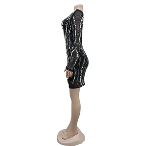 Detail of black mesh dress featuring dense white pearls and sparkling rhinestone patterns