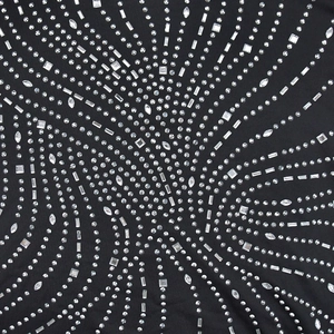 Vue macro des strass étincelants aux formes géométriques sur le tissu noir de la robe