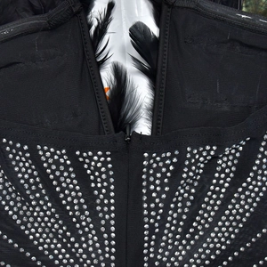 Detail eines schwarzen Strass-Jumpsuits mit Federbesatz und verdecktem Reißverschluss