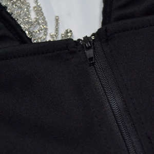 Gros plan d'une robe noire avec fermeture éclair invisible et détail de bretelle strass