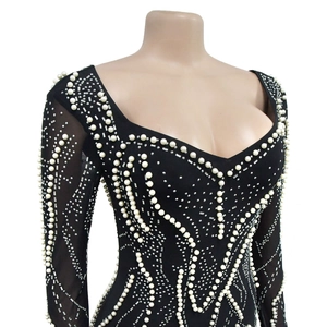 Detail of mesh sleeves and wave patterns of pearls and rhinestones on a black mini dress