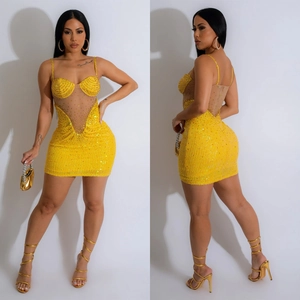 Détail de la mini robe jaune à paillettes avec patchwork en résille et corsage strass