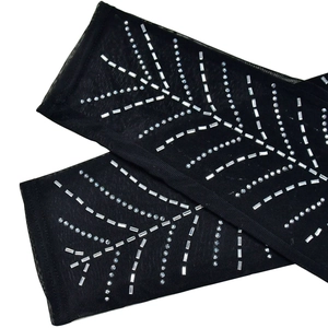 Detail eines schwarzen Mesh-Overalls mit silbernen Strasssteinen im Federmuster