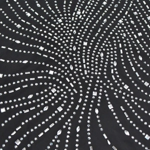 Détail de strass argentés rayonnants de formes mixtes sur le tissu noir de la robe licou