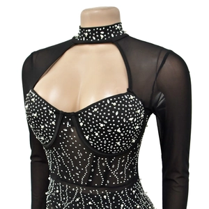 Détail d'une combinaison noire à strass avec manches en tulle et ornements de perles