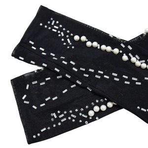 Detail of black mesh sleeve with pearls and sparkling rhinestones in geometric patterns