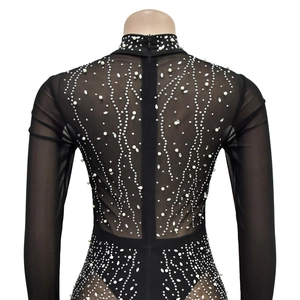 Détail d'un body en mesh transparent avec strass scintillants et perles sur fond noir