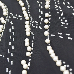 Close-up of black mesh dress featuring elegant white pearls and rectangle rhinestone details