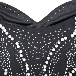 Macro detail of V-neckline with faux pearls, rhinestones and sequins on black dress