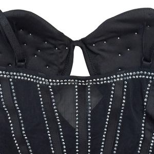 Détail d'un haut corset noir avec tissu en maille, structure baleinée et rangées de strass