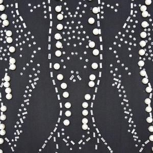 Detail of mesh dress featuring intricate faux pearls and baguette crystals on black fabric