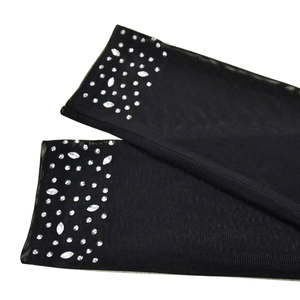 Détail de manchons en maille noire ornés de strass argentés brillants sur les poignets