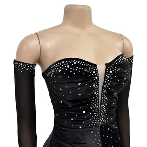 Dettaglio dell'abito in velluto nero con strass brillanti e maniche lunghe in mesh velato