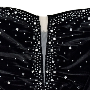 Dettaglio di un abito in velluto nero con strass di lusso e scollo a V in rete trasparente