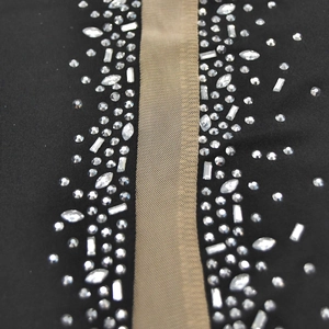 Close-up of sparkling rhinestones on black fabric and sheer mesh of sleeveless dress