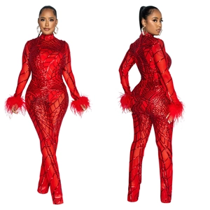 Detailed view of red mesh jumpsuit featuring geometric sequins and fluffy feather cuffs
