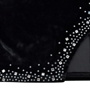 Dettaglio del vestito in velluto nero con spacco laterale e decorazioni di strass lucidi