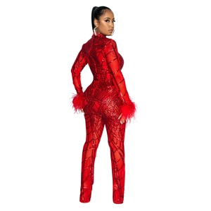 Detailed view of red sequin jumpsuit featuring sheer mesh fabric and fluffy feather cuffs