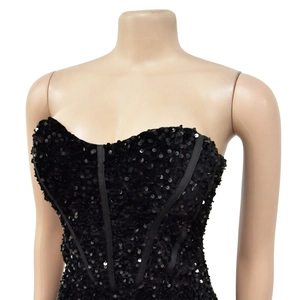 Dettaglio dell'abito a corsetto nero con paillettes e stecche strutturali lucenti