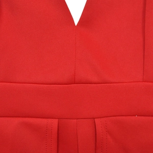 Détail macro d'une combinaison rouge avec col en V, taille froncée et texture fine du tissu