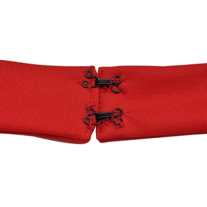 Détail des fermoirs à crochets en métal noir sur le tissu en maille rouge de la combinaison