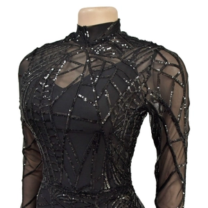 Close-up of black mesh top with geometric silver sequins and sheer long sleeves