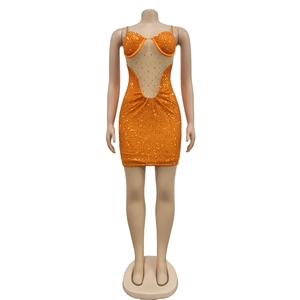 Détail d'une robe courte orange à paillettes avec découpe en résille et strass scintillants