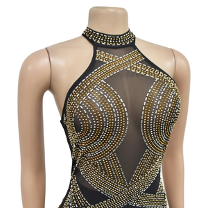 Détail d'un body en résille noire avec des motifs complexes en strass dorés et argentés